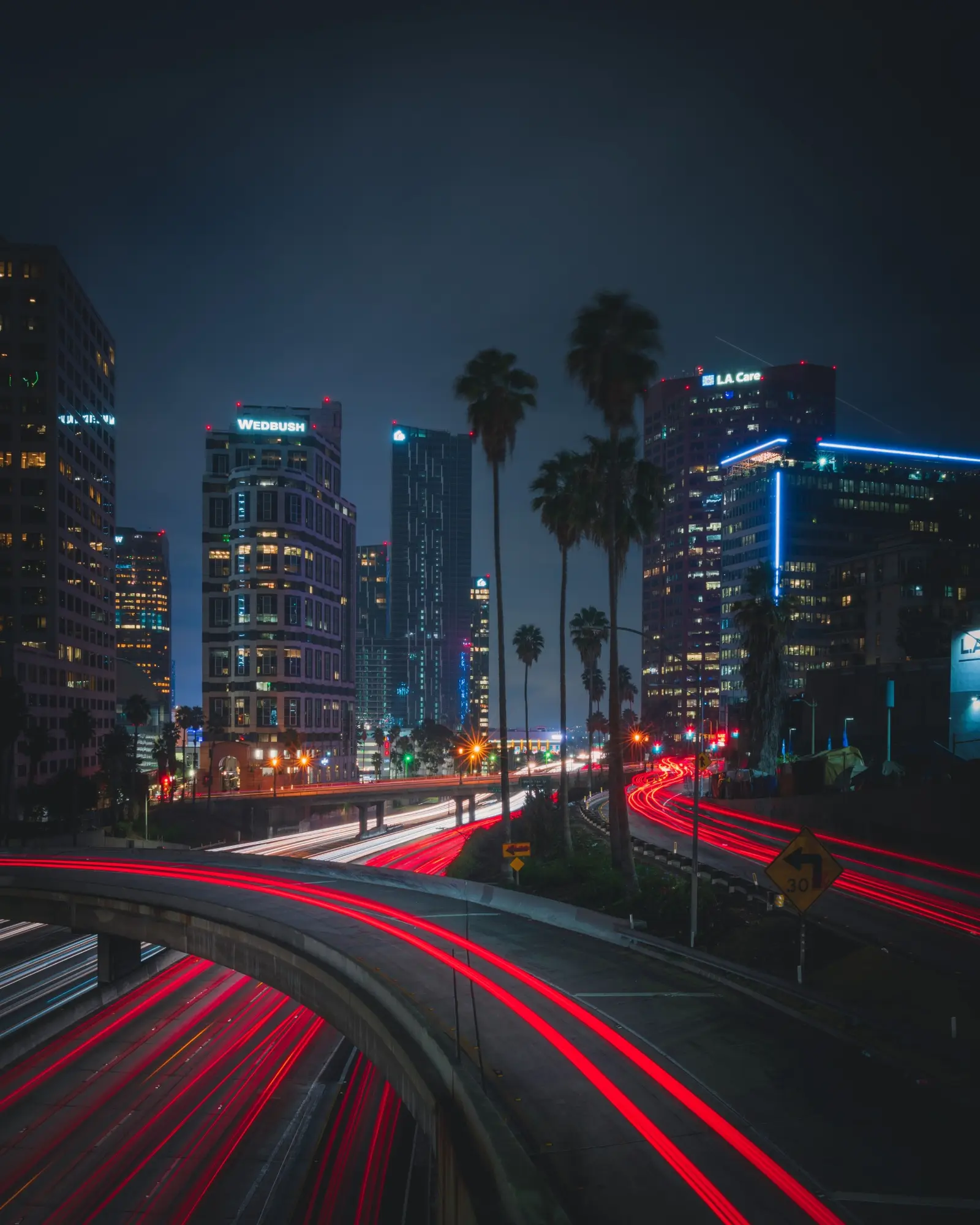 City freeway and skyline illuminated by nighttime traffic trails
